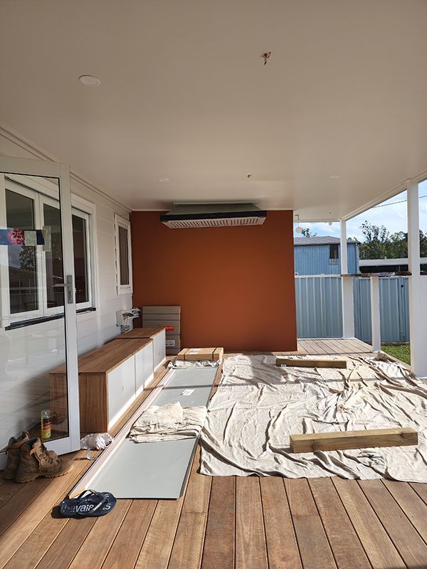 A Wooden Deck Is Being Painted On The Side Of A House With Cabinet — Entire Trades in Port Stephens, NSW