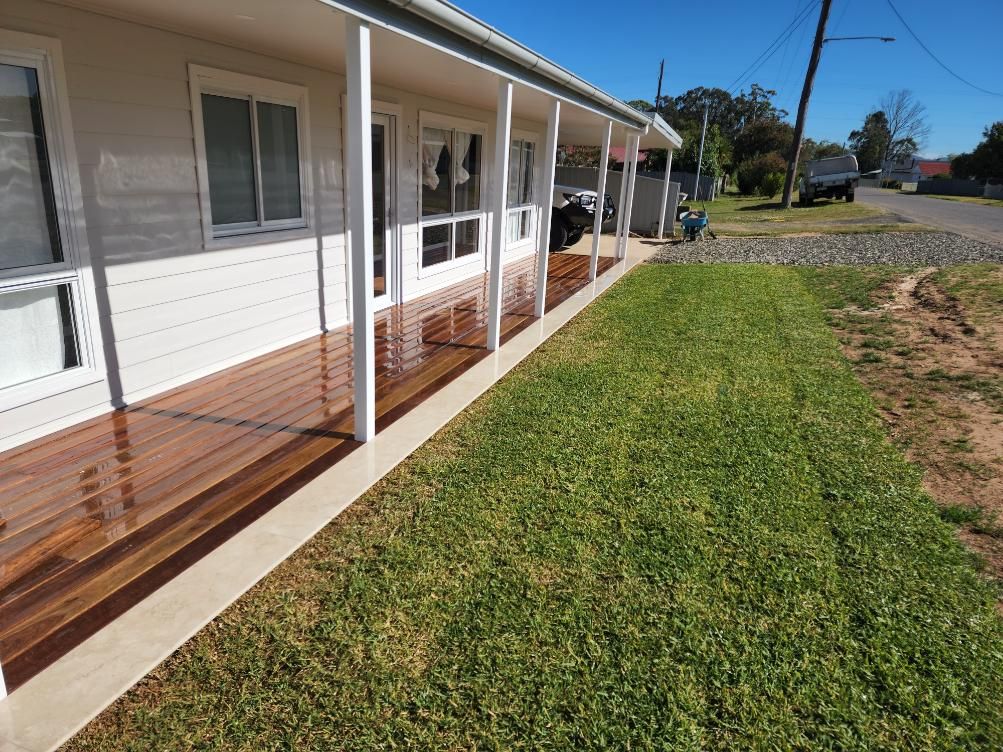 A House with A Wooden Deck and A Lawn in Front of It — Entire Trades in Maitland, NSW
