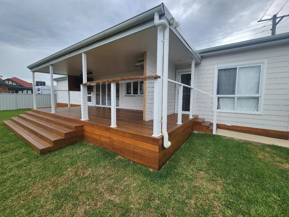 A White House with A Wooden Deck and Stairs in Front of It — Entire Trades in Maitland, NSW
