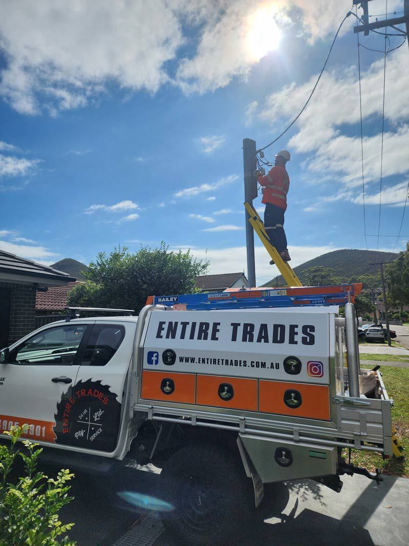 Entire Trades Vehicle With A Man Is Climbing A Ladder On The Electricity Pole — Entire Trades in Maitland, NSW