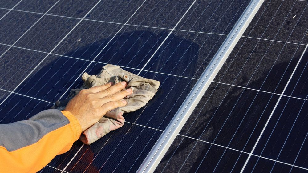 Person Cleaning Solar Panels On Roof — Entire Trades in Singleton, NSW