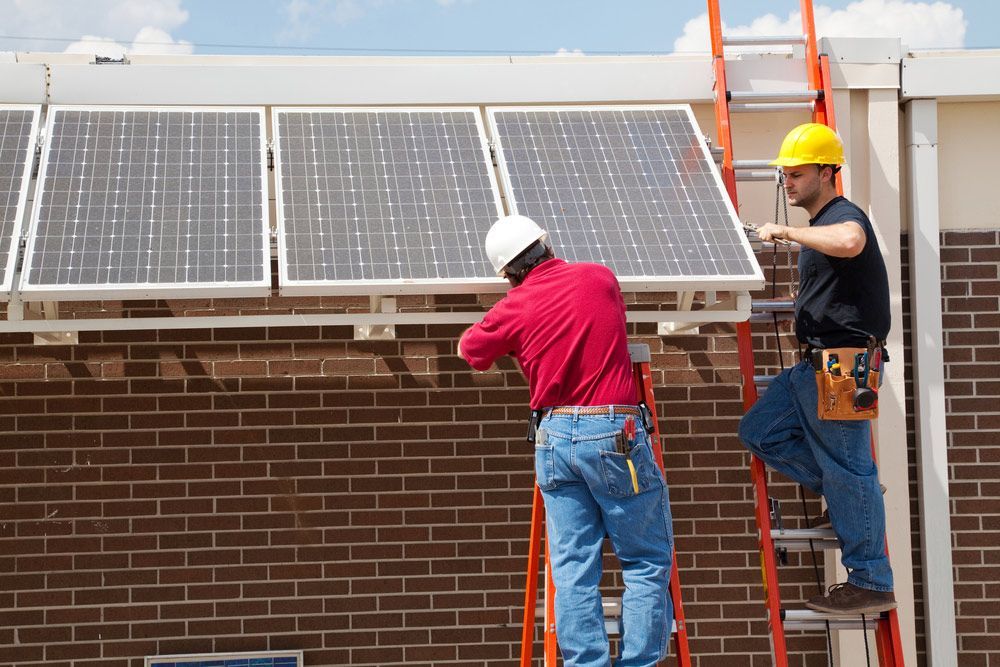 Two Electricians Installing Solar Panels On A Building — Entire Trades in Maitland, NSW