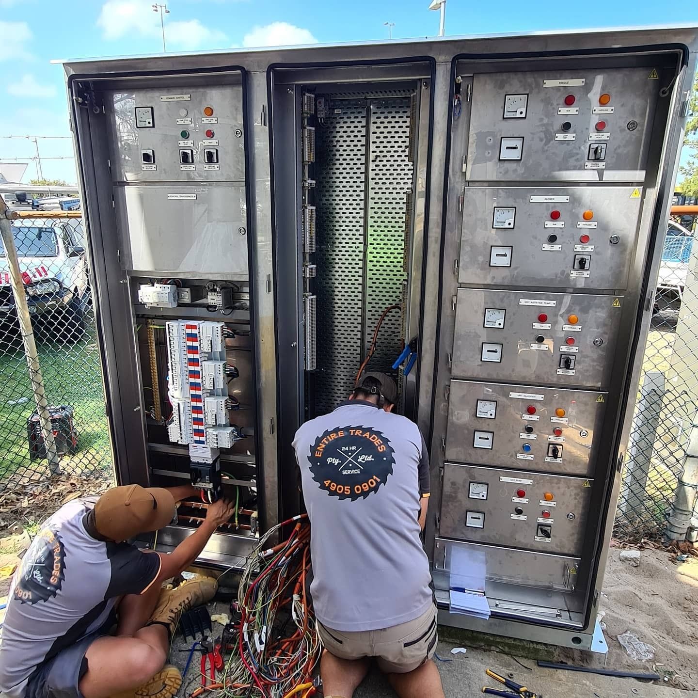 Two Men Fixing Wiring in Switchboard Box — Entire Trades in Maitland, NSW