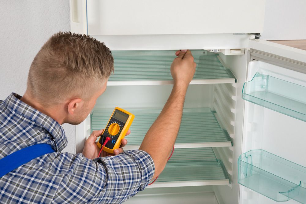Male Technician Checking Fridge With Digital Multimeter — Entire Trades in Singleton, NSW