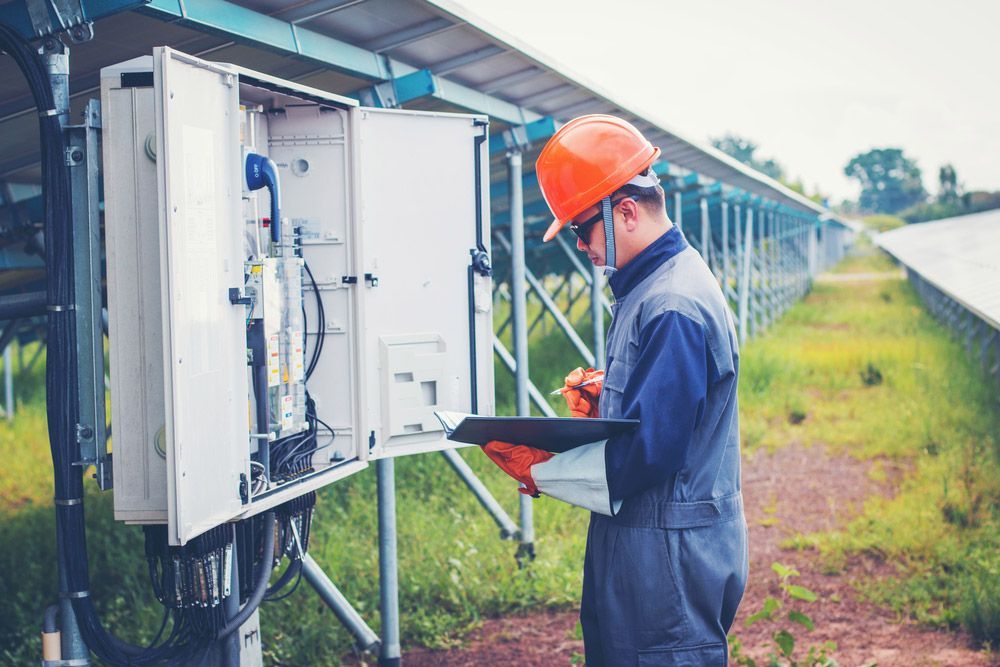 Man In Blue Uniform Checking Status Of The Solar Inverter — Entire Trades in Cessnock, NSW