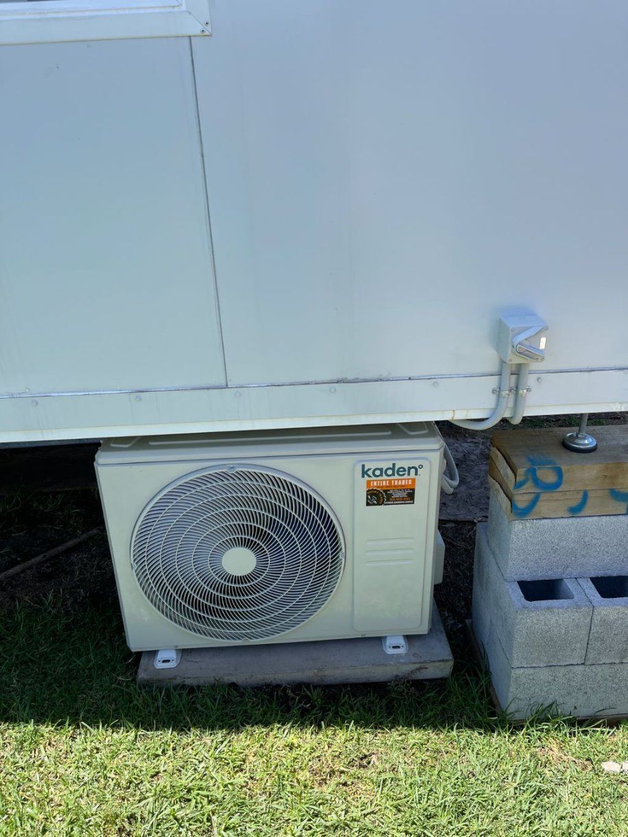 A Fan Is Sitting on Top of A Concrete Block Next to A Building — Entire Trades in Maitland, NSW