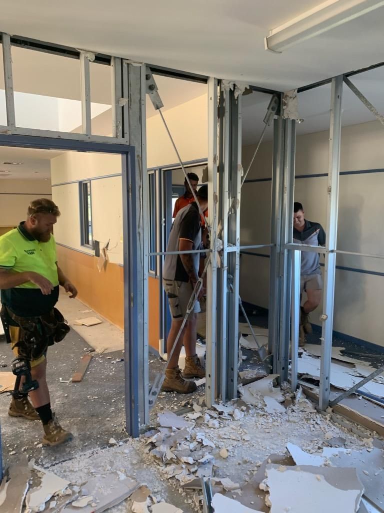 A Group of Construction Workers Are Working on A Building — Entire Trades in Maitland, NSW