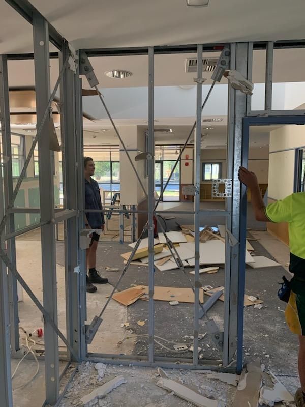 A Man in A Yellow Shirt Is Working on A Building — Entire Trades in Maitland, NSW