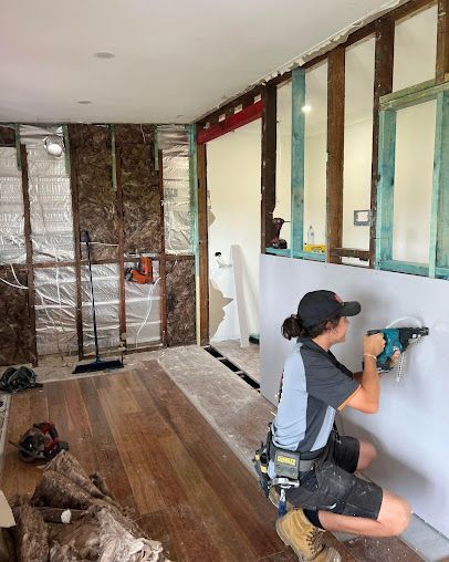 A Man Is Working On A Wall With A Drill In A Room — Entire Trades in Singleton, NSW