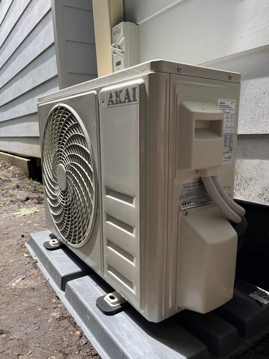 A White Air Conditioner Is Sitting Outside of A Building — Entire Trades in Maitland, NSW