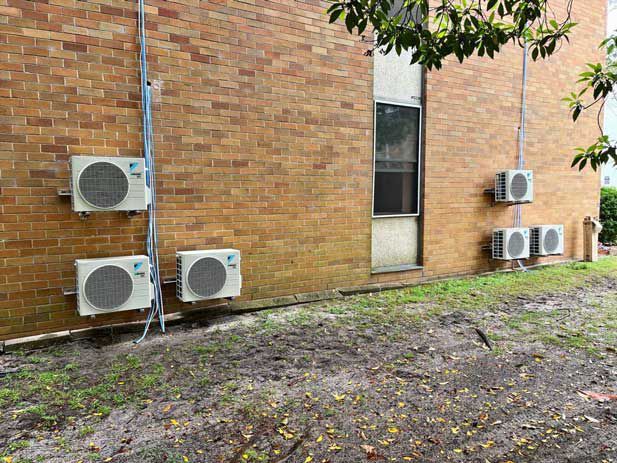 Air Conditioners On The Side Of A Brick Building Installed — Entire Trades in Port Stephens, NSW