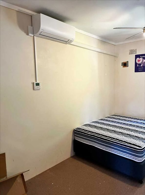 A Bedroom With A Bed , Air Conditioner Mounted On Wall — Entire Trades in Port Stephens, NSW