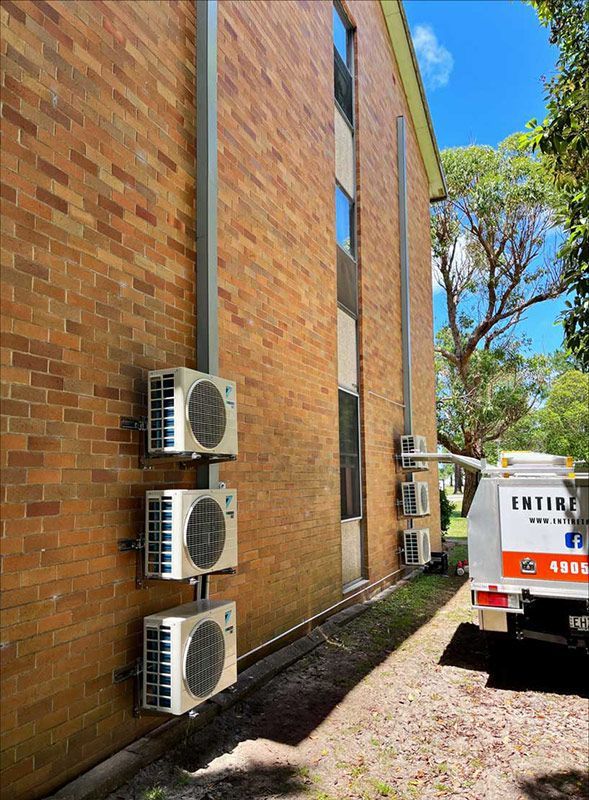 An Entire Trades Truck Parked Next To A Building With Air Conditioning Units — Entire Trades in Cessnock, NSW
