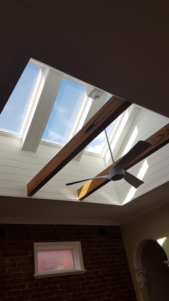 A Ceiling Fan Is Hanging from The Ceiling of A Room with A Skylight — Entire Trades in Maitland, NSW
