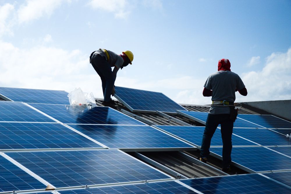 Two Workers Wearing Safety Gear Installing Solar Panels