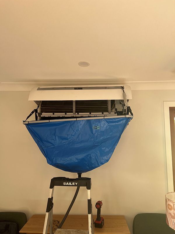 A Blue Bag Is Hanging From The Air Conditioning Cleaning — Entire Trades in Central Coast, NSW