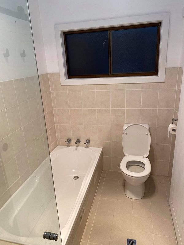 A Bathroom With A Toilet, Bathtub And Window — Entire Trades in Maitland, NSW