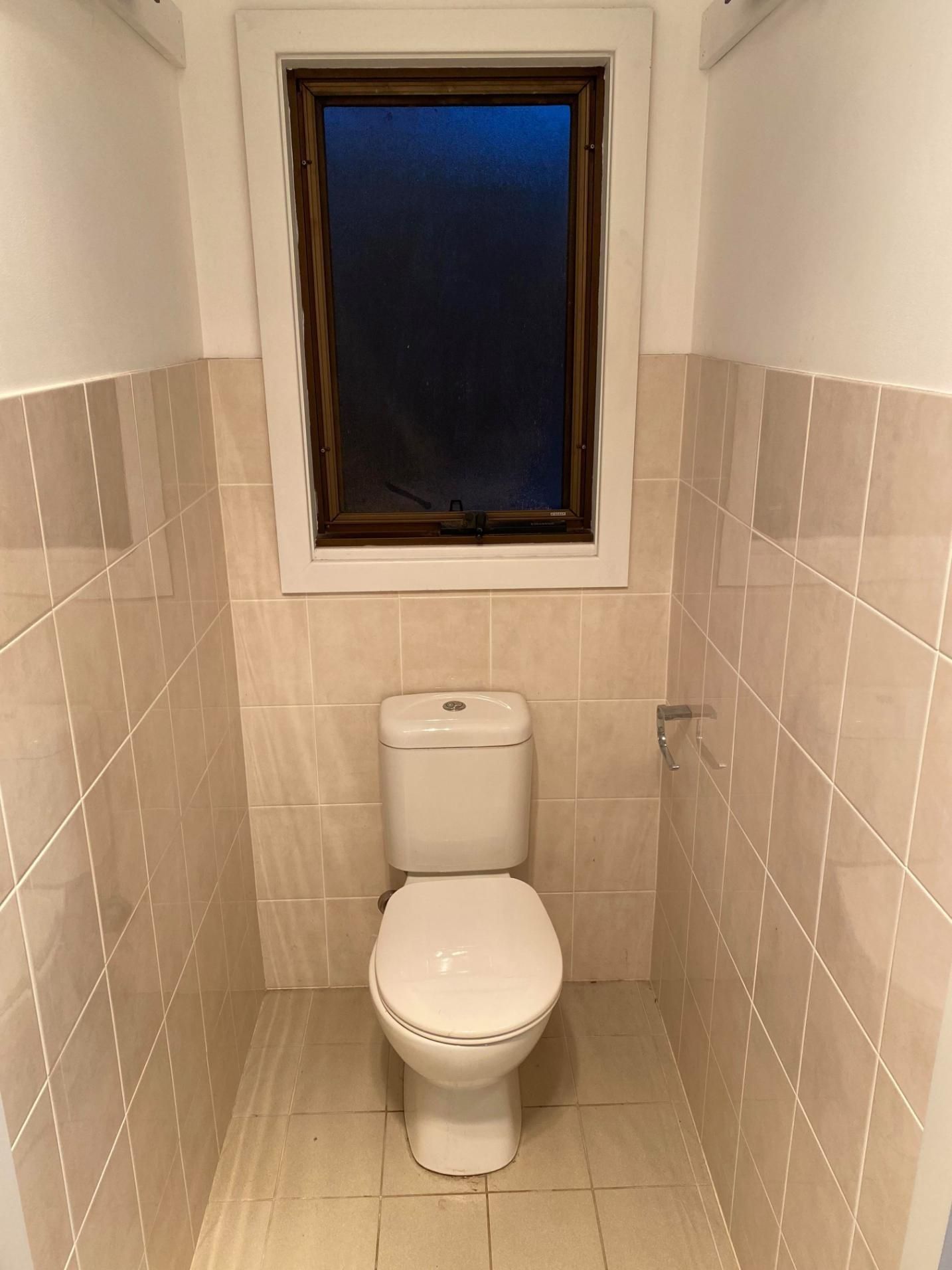 A Toilet Is Sitting in A Small Bathroom Next to A Window — Entire Trades in Maitland, NSW