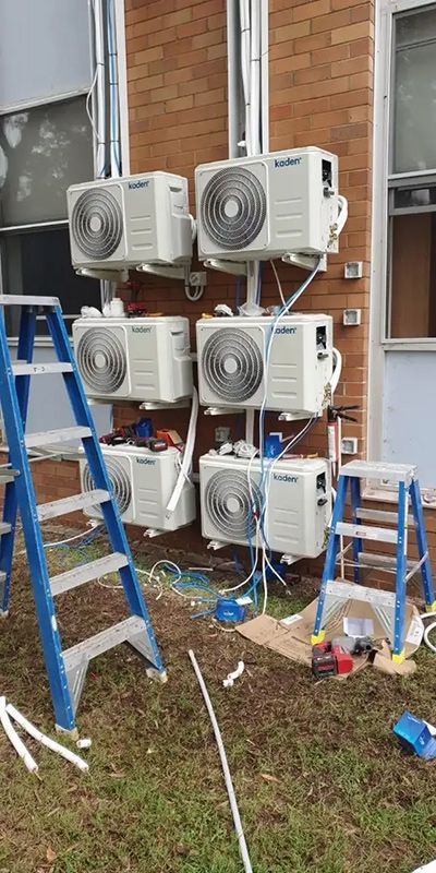 A Bunch Of Air Conditioners Are Being Installed On The Side Of A Building — Entire Trades in Maitland, NSW