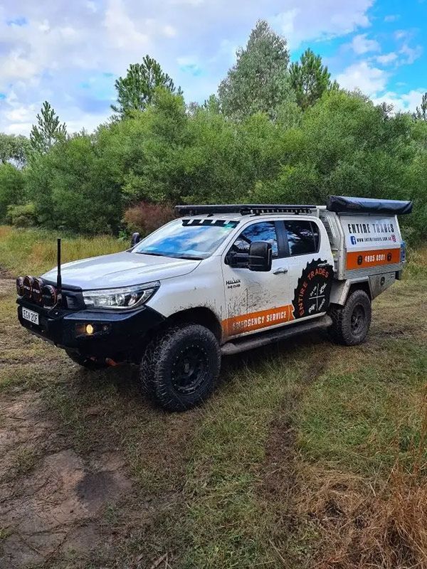 A White Entire Trades Truck With A Canopy Is Parked In A Grassy Field — Entire Trades in Singleton, NSW