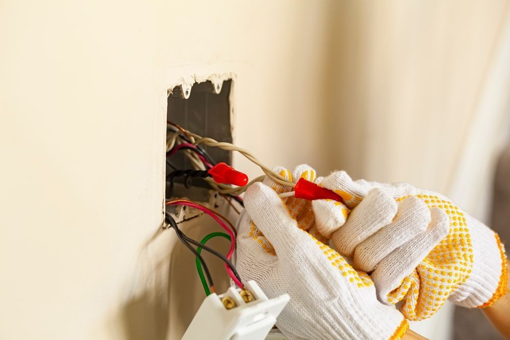 Electrician Installing A Switch On The Wall — Entire Trades in Maitland, NSW