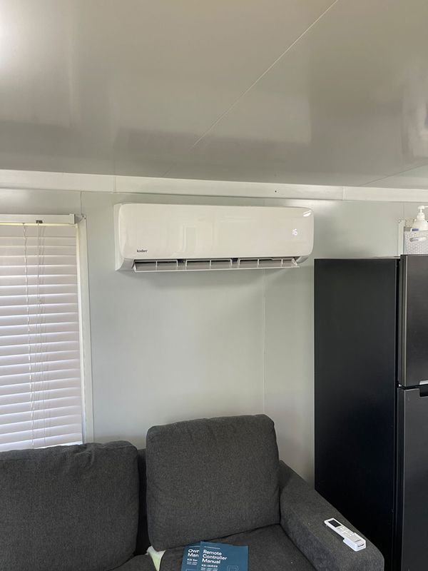 A Living Room With A Couch, Refrigerator And Air Conditioner — Entire Trades in Maitland, NSW