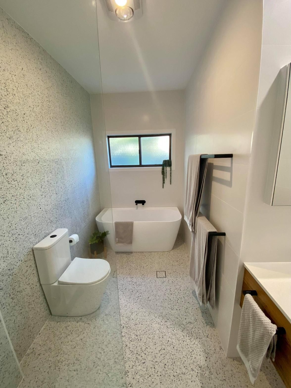 A Bathroom with A Bathtub, Toilet,  Sink and Window — Entire Trades in Maitland, NSW