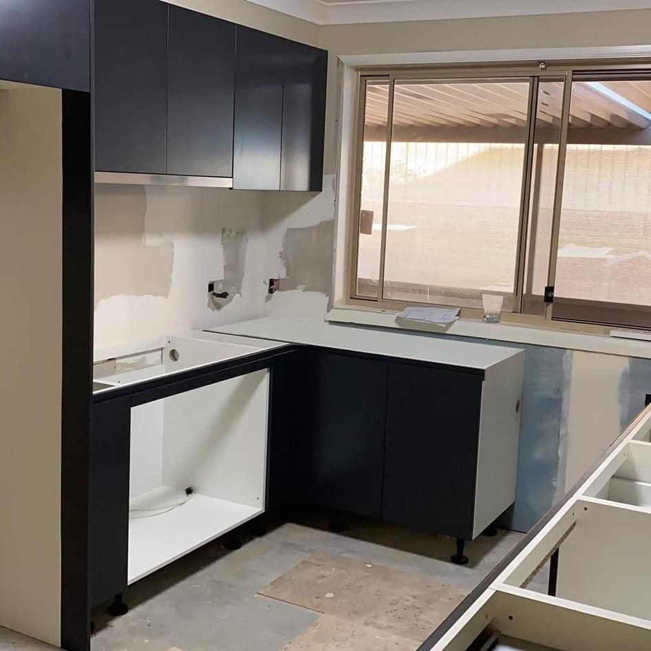 A Kitchen Under Construction with Black Cabinets and White Counter Tops — Entire Trades in Maitland, NSW