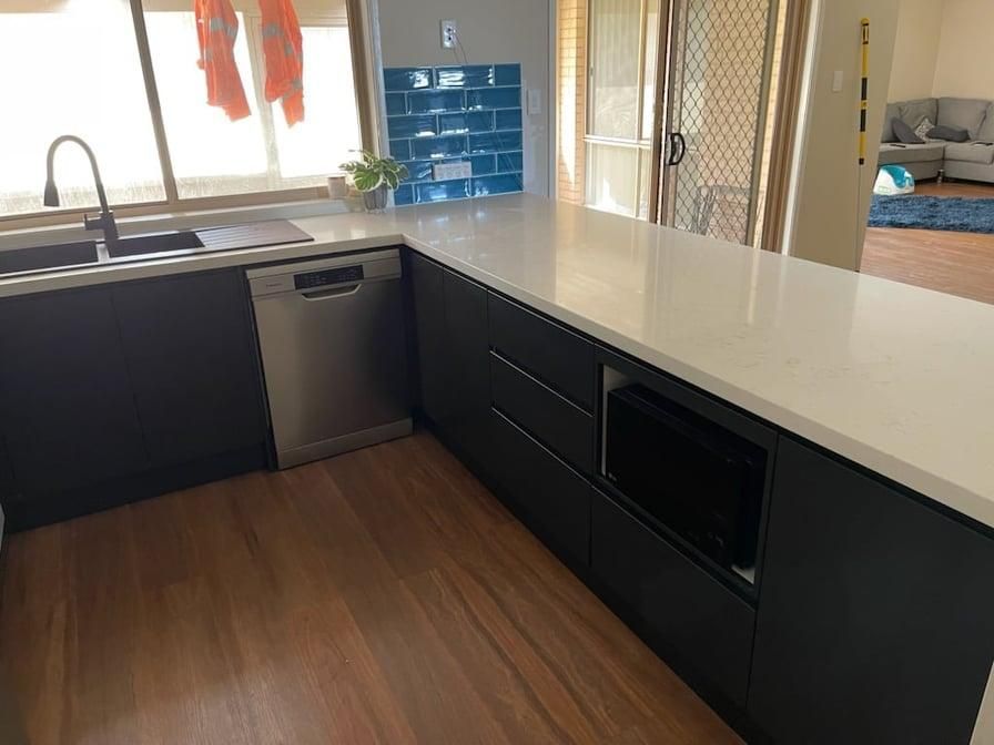 A Kitchen with Black Cabinets and A White Counter Top — Entire Trades in Maitland, NSW