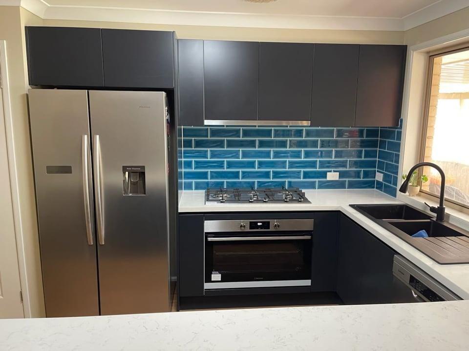 A Kitchen with Stainless Steel Appliances and Blue Tiles — Entire Trades in Maitland, NSW