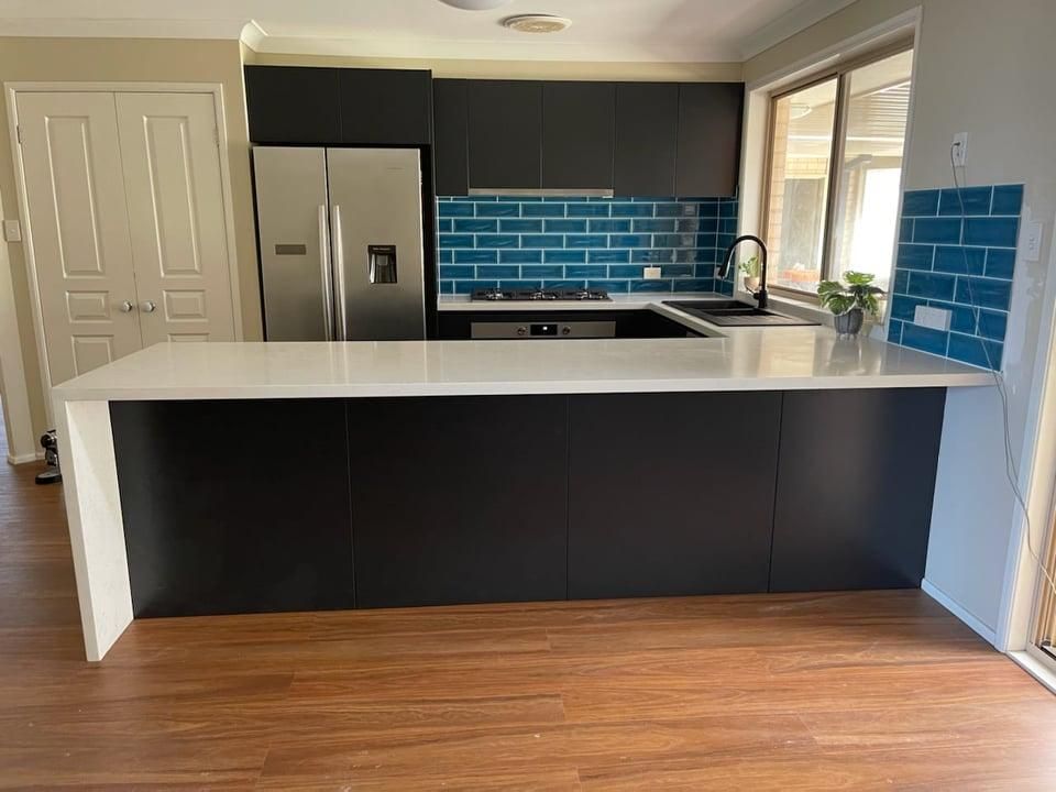 A Kitchen with Black Cabinets and A White Counter Top — Entire Trades in Maitland, NSW