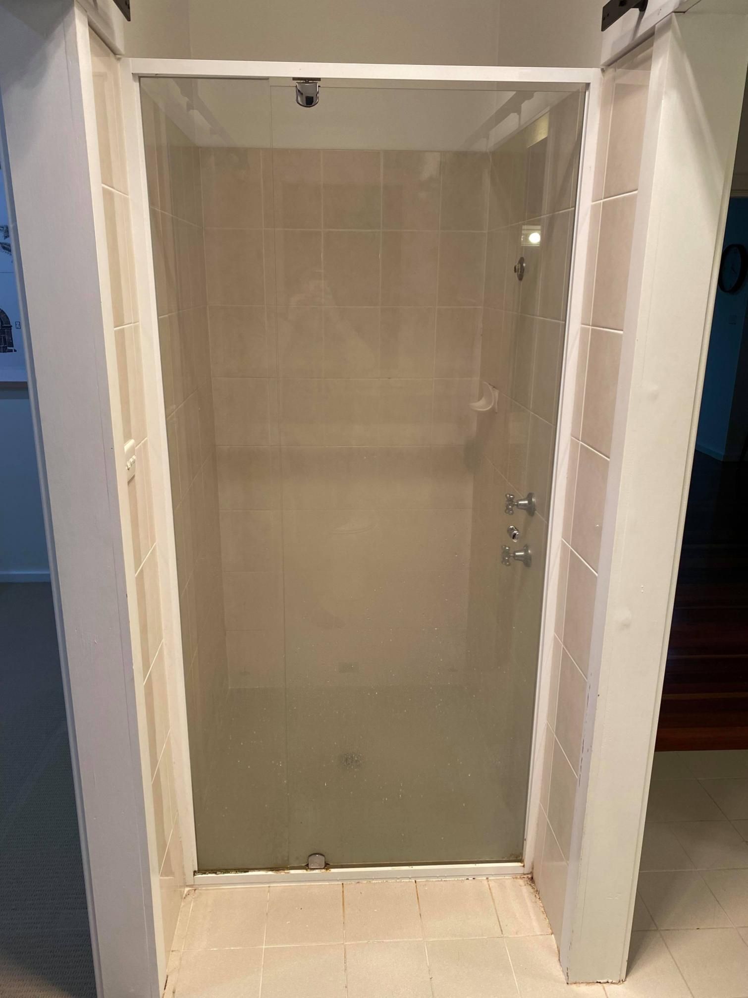 An Empty Shower Stall with A Glass Door in A Bathroom — Entire Trades in Maitland, NSW