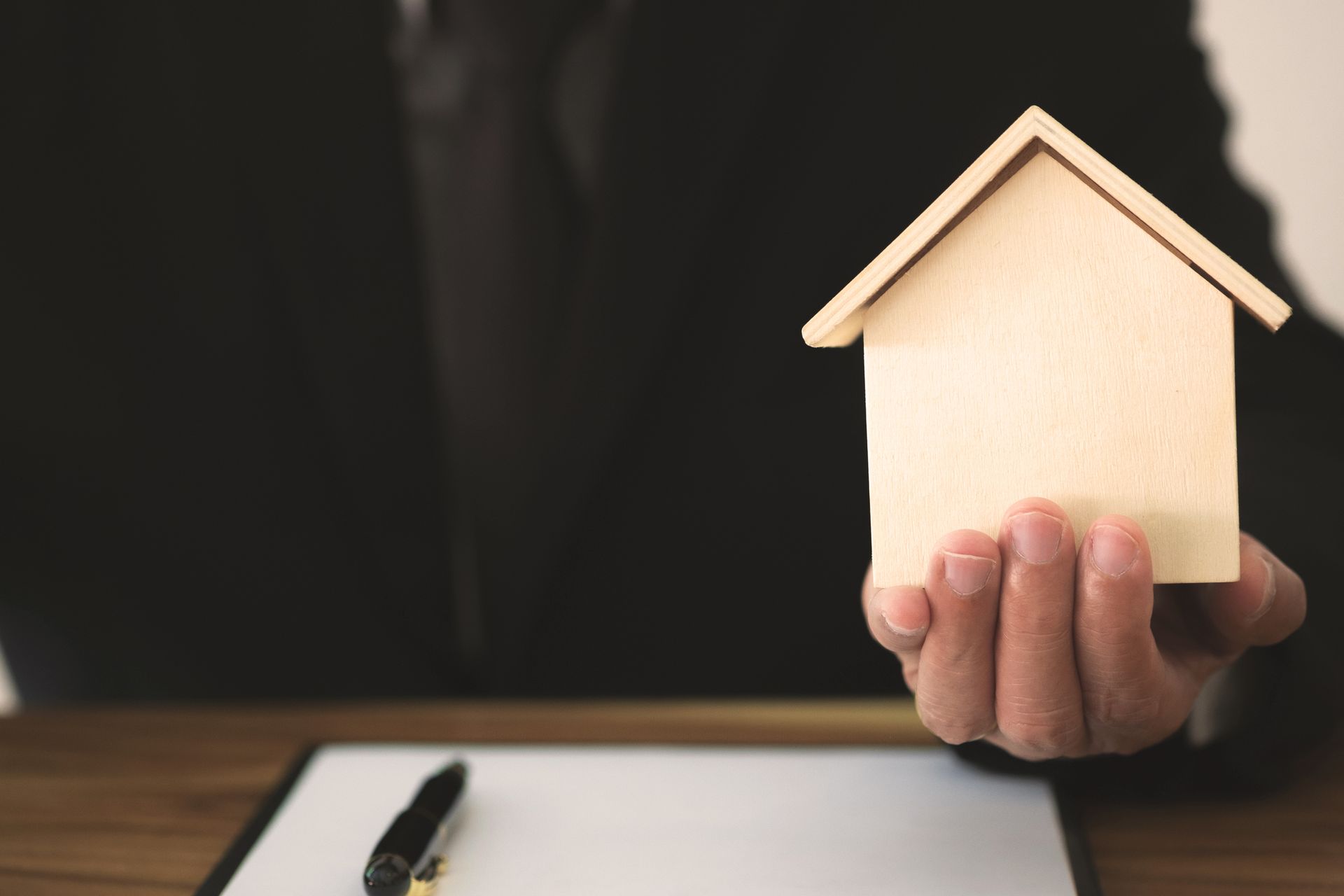 Lawyer holding a small house in hand, close-up view symbolizing expert property conveyancing