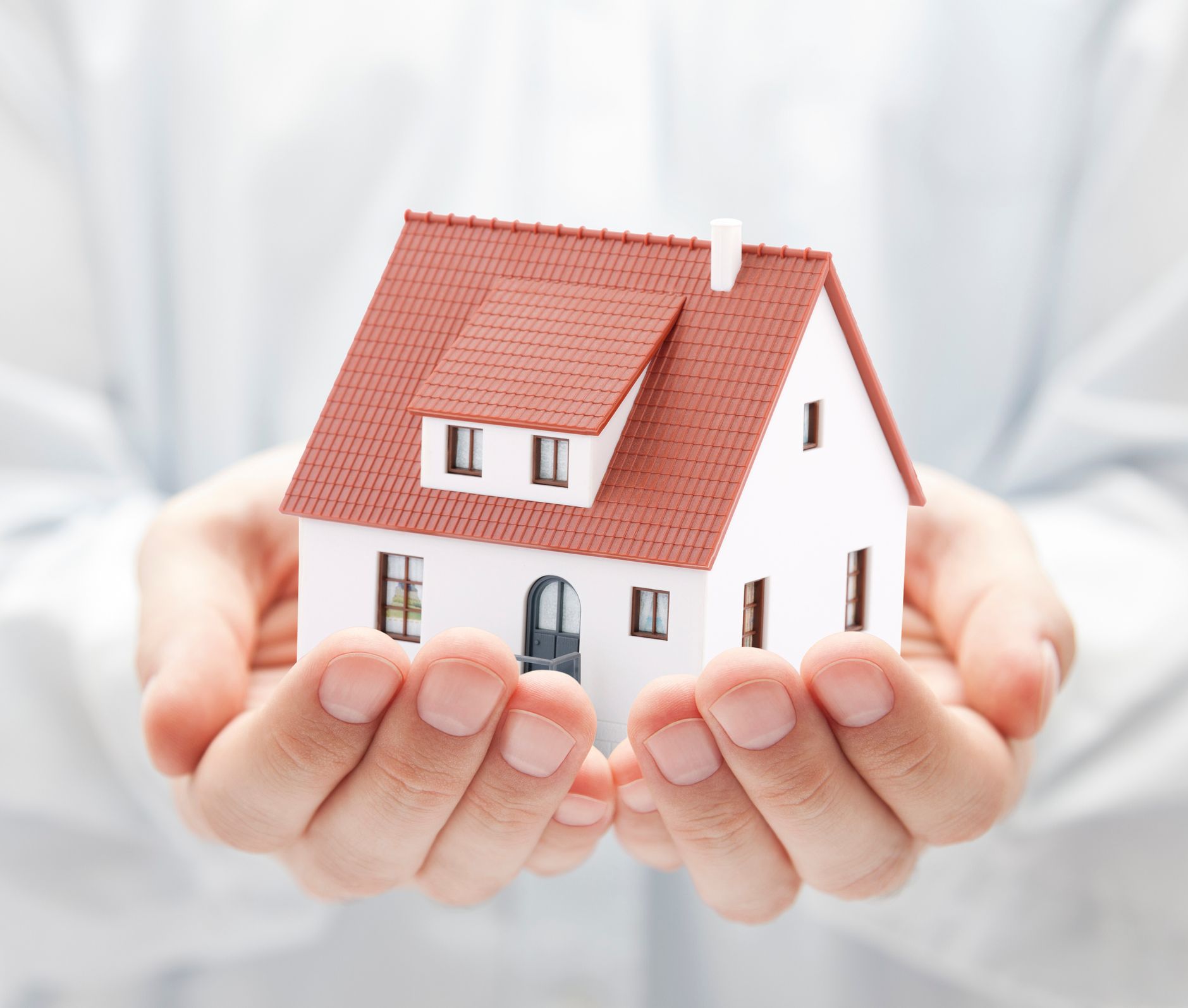 Real estate conveyancing symbolized by hands gently holding a nice house, close-up perspective