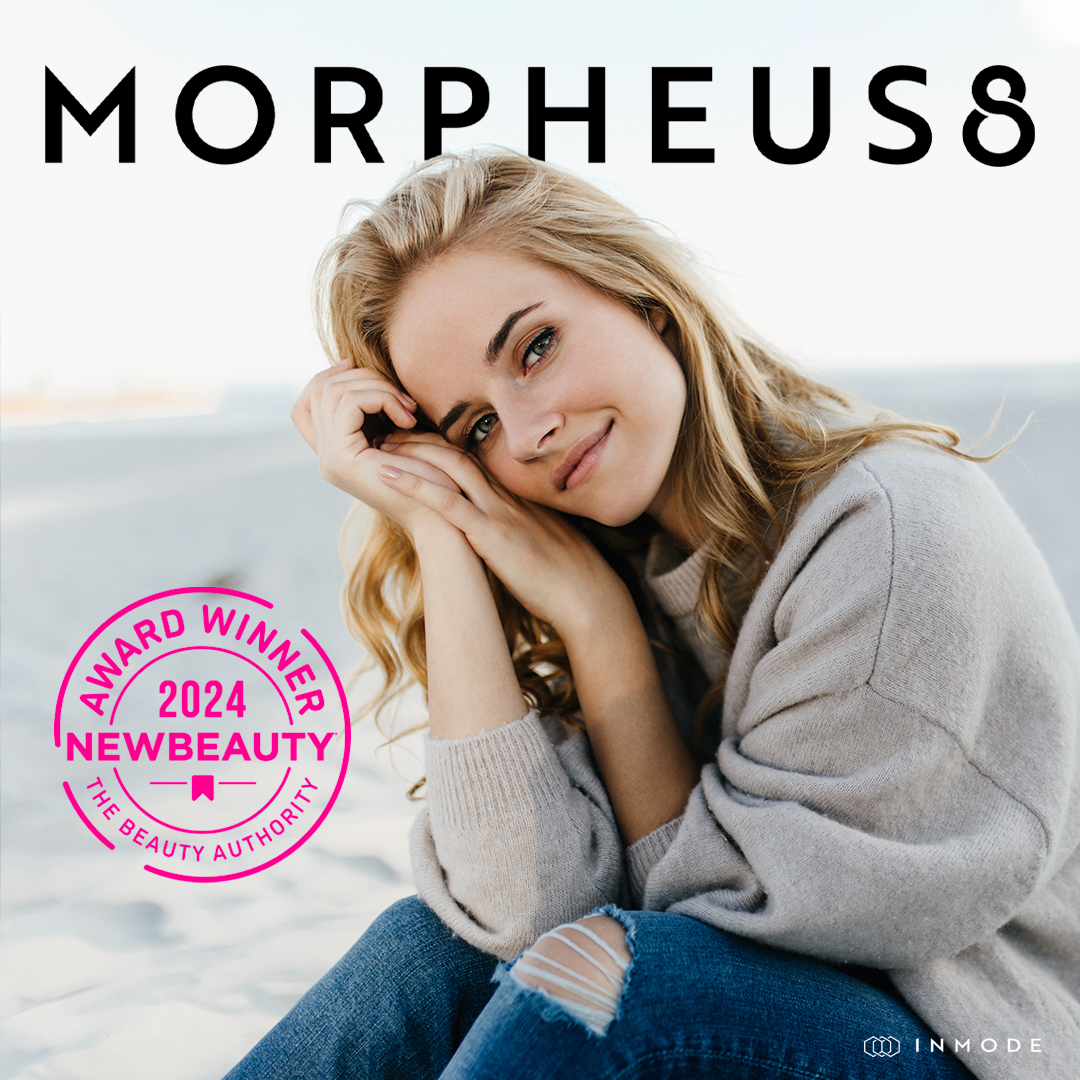 A woman is sitting on the beach in front of a sign that says morpheus8