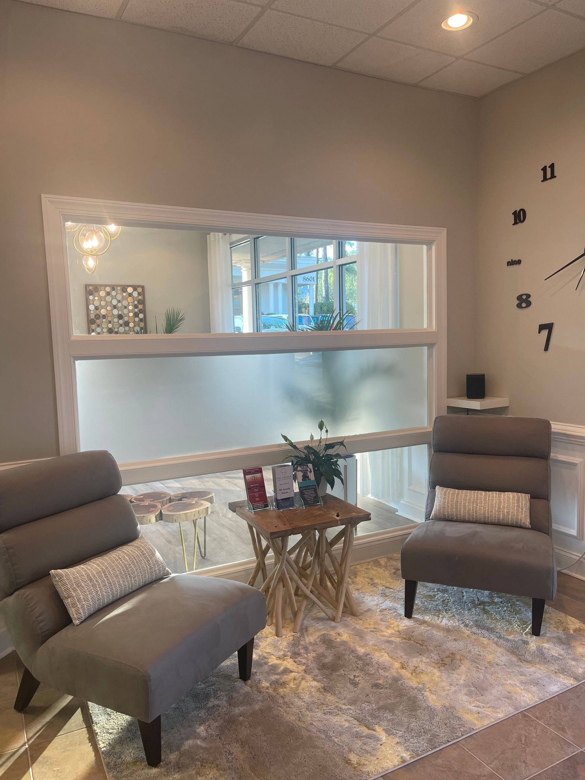 A living room with two chairs and a clock on the wall.