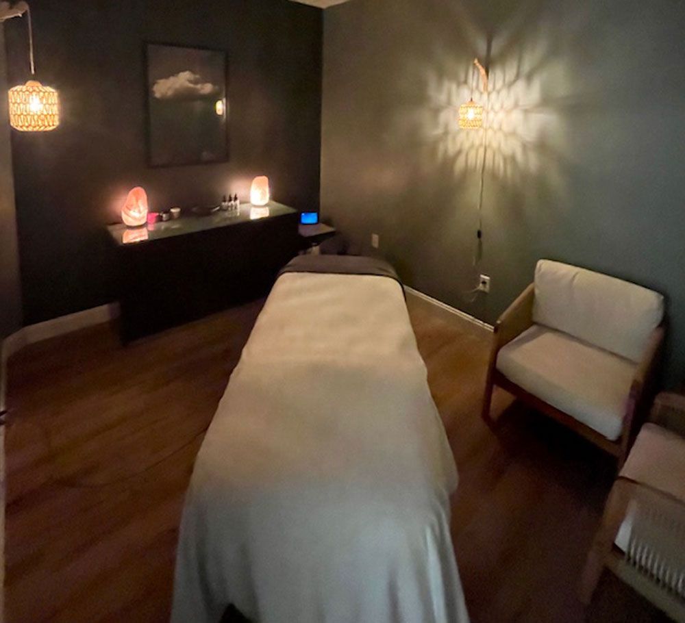 A massage room with a bed , couch , and chandelier.