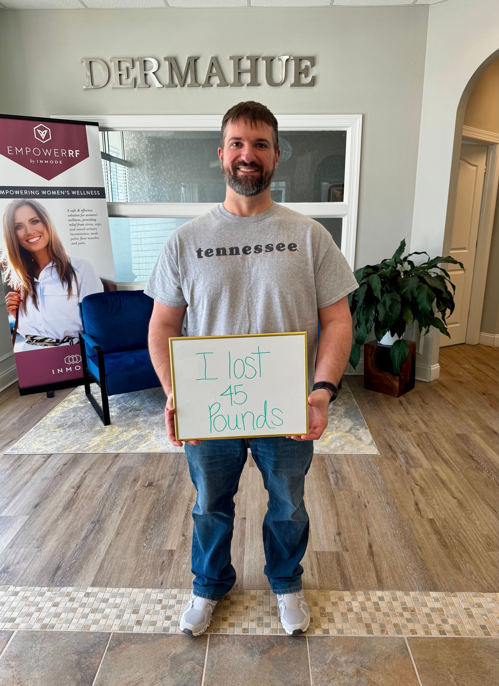 Man holding sign, smiling, in front of 