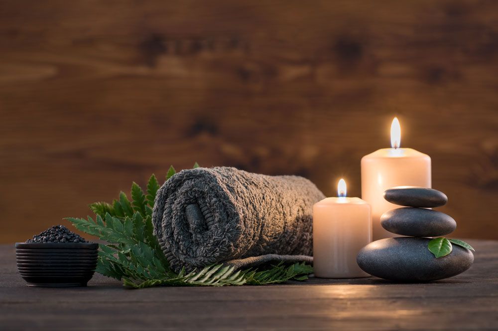 A wooden table topped with towels , candles , and rocks.