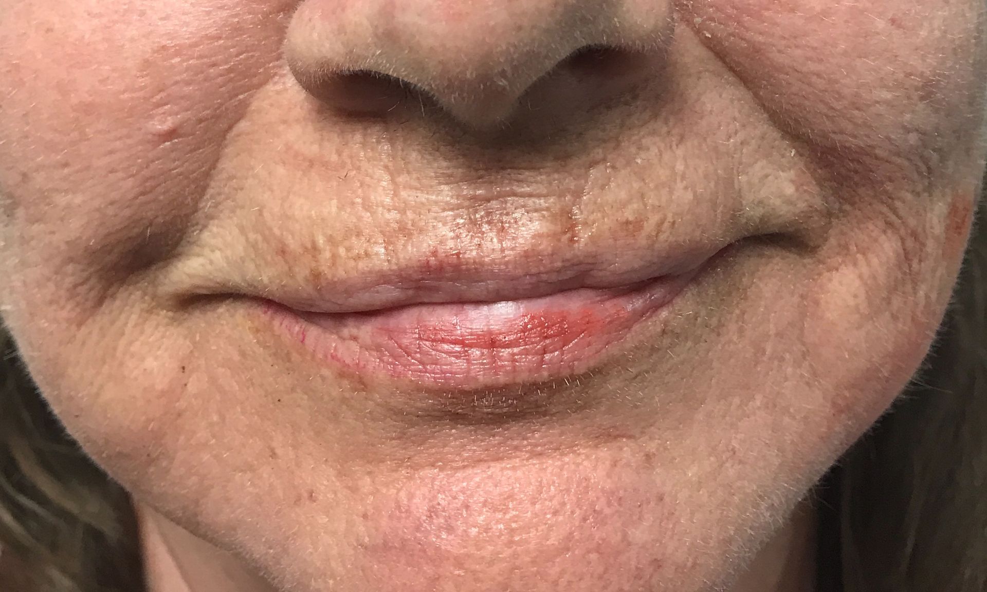 A close up of a woman 's face with wrinkles and red lips.