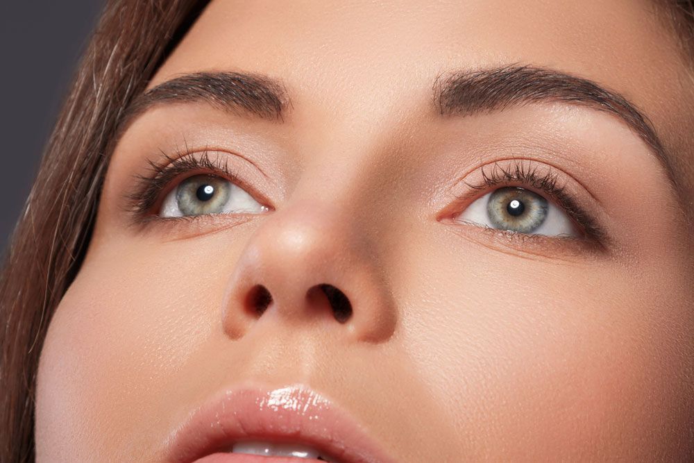 A close up of a woman 's face with green eyes looking up.