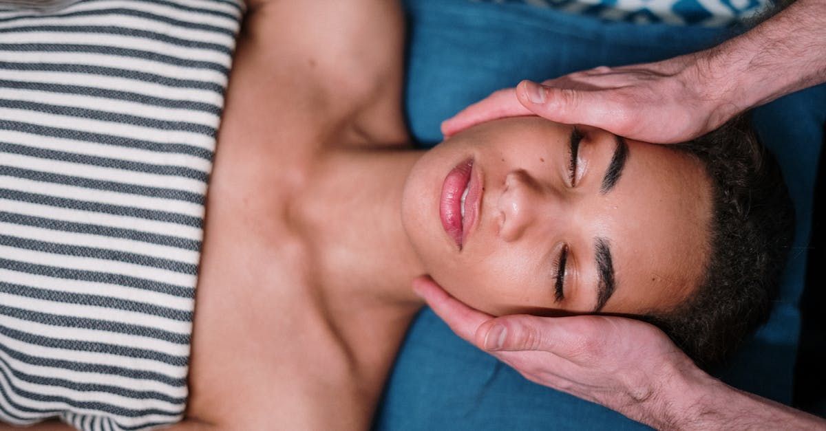 A woman is laying on a bed getting a head massage.