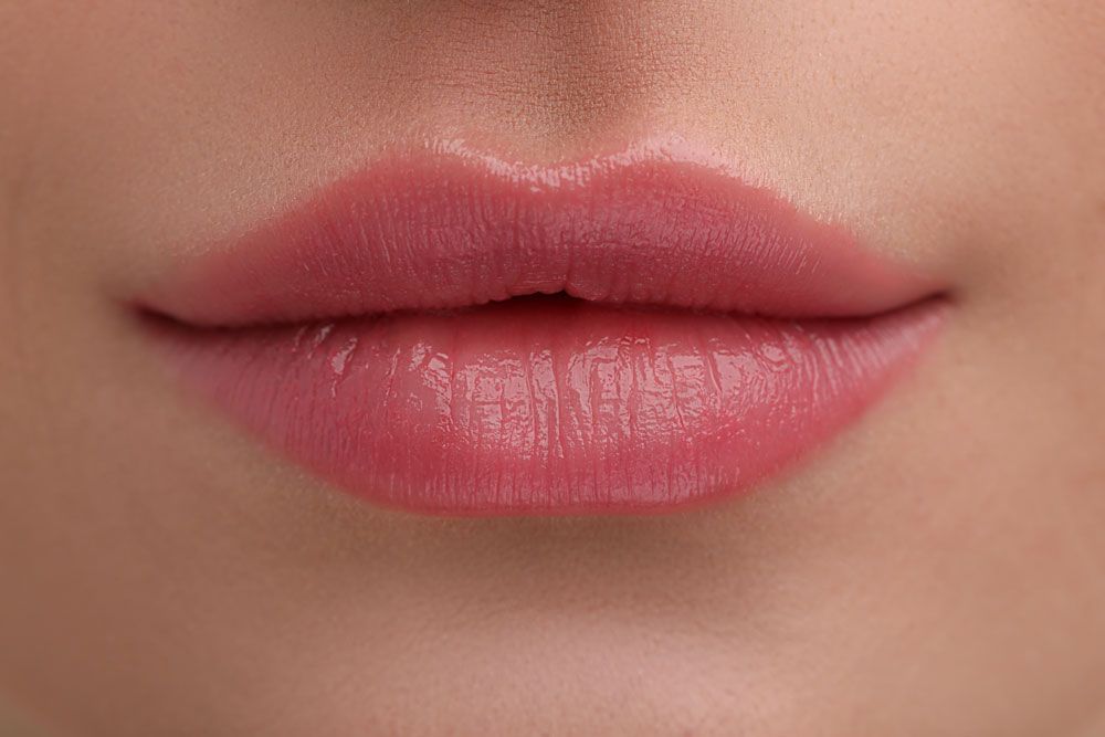 A woman is getting a botox injection in her lips.