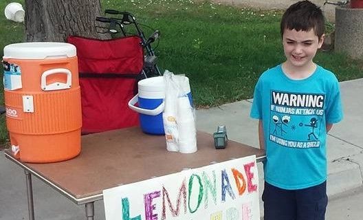Child standing in front of his lemonade stand