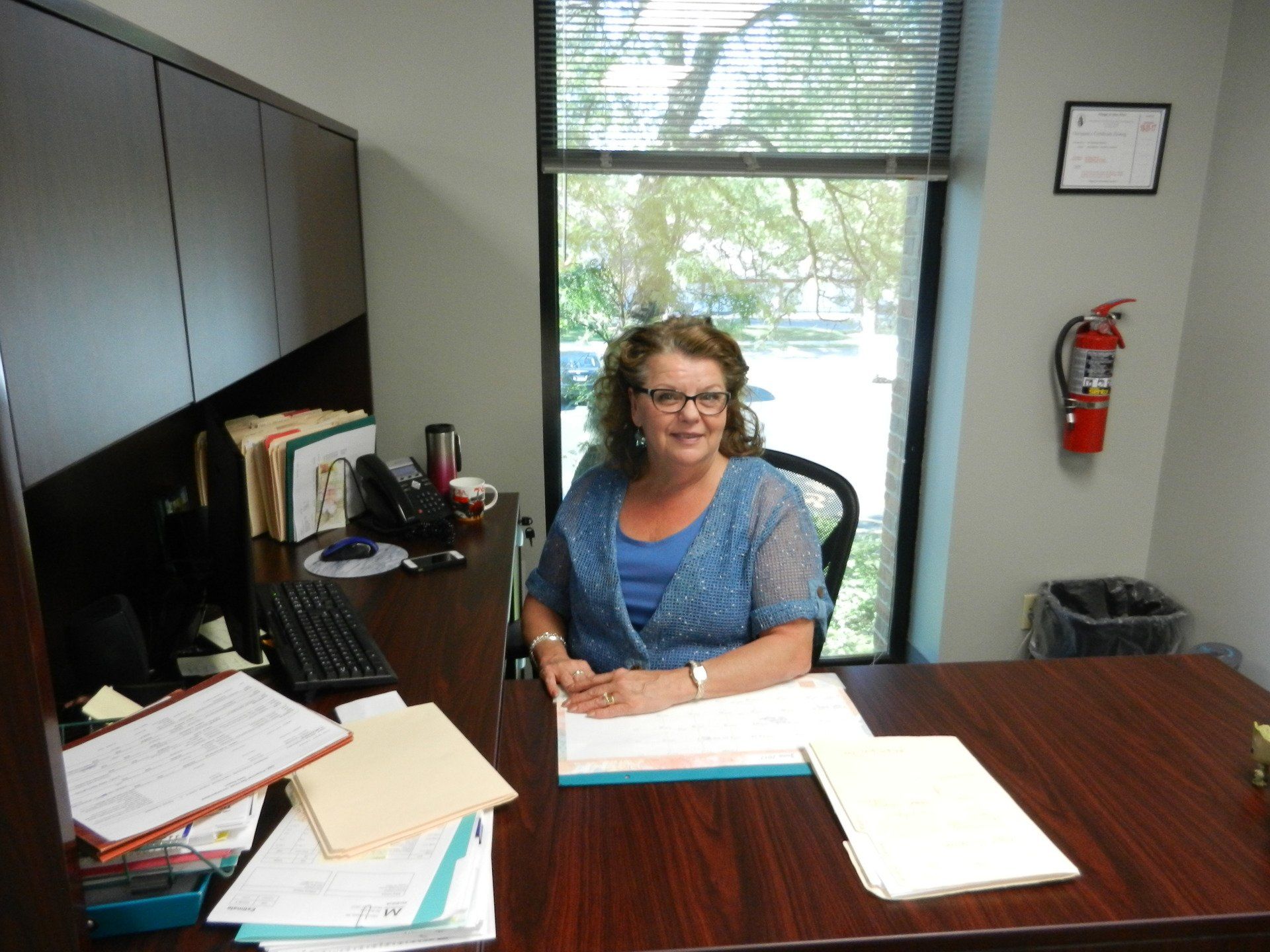 A woman is sitting at a desk in front of a window
