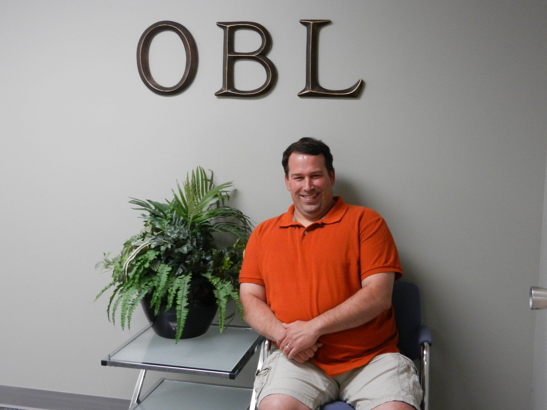 A man sitting in front of a sign that says obl