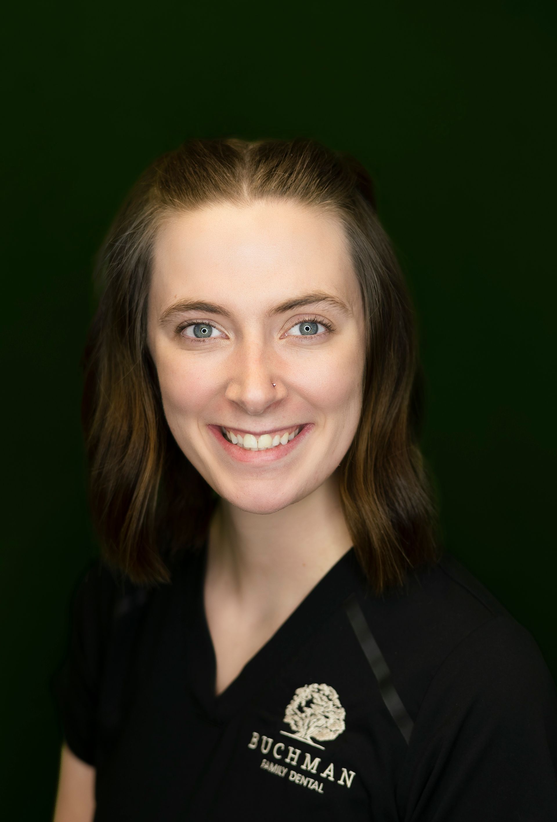 A woman in a black scrub top is smiling for the camera.