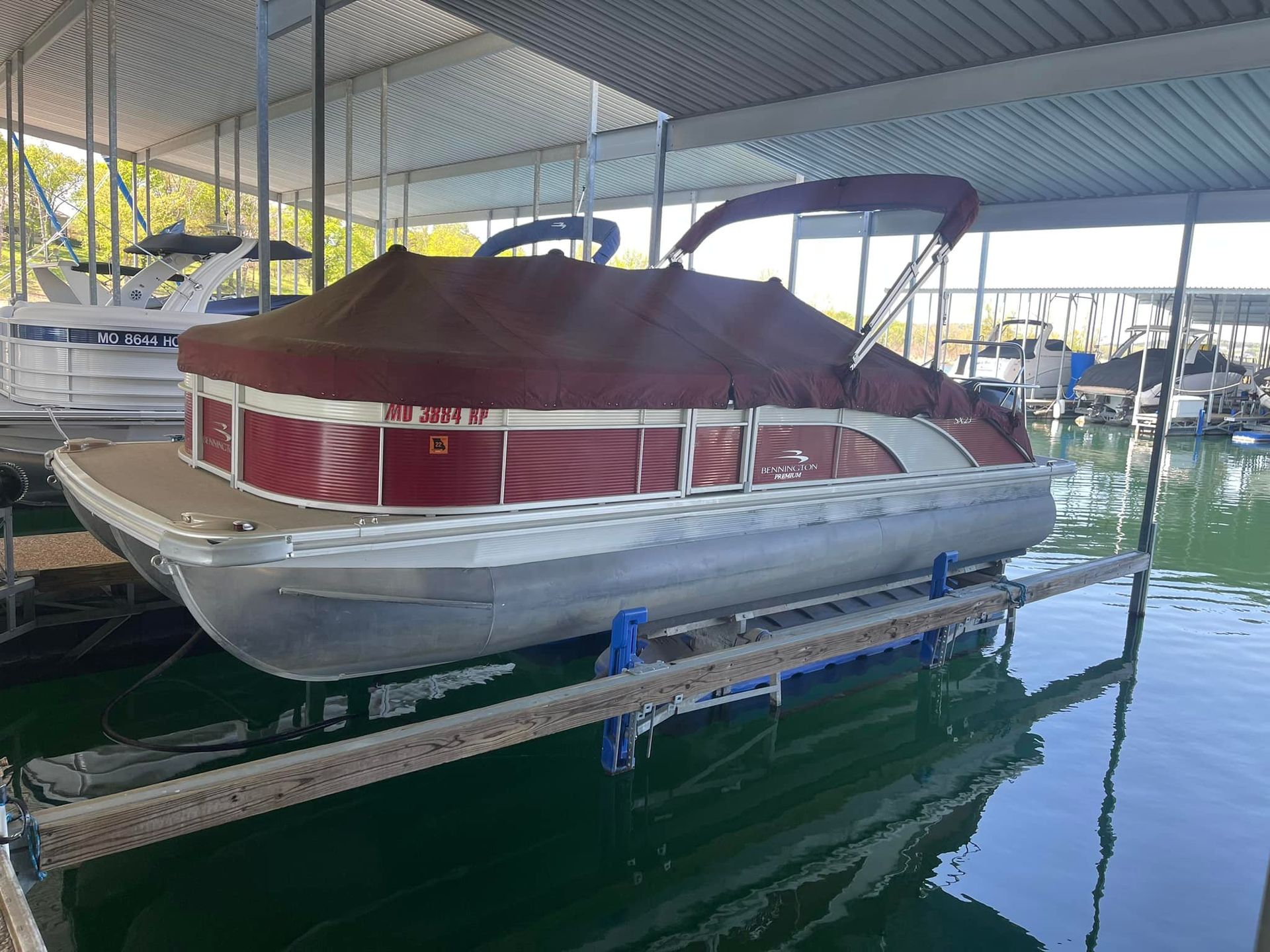 A red pontoon boat is sitting in a dock.