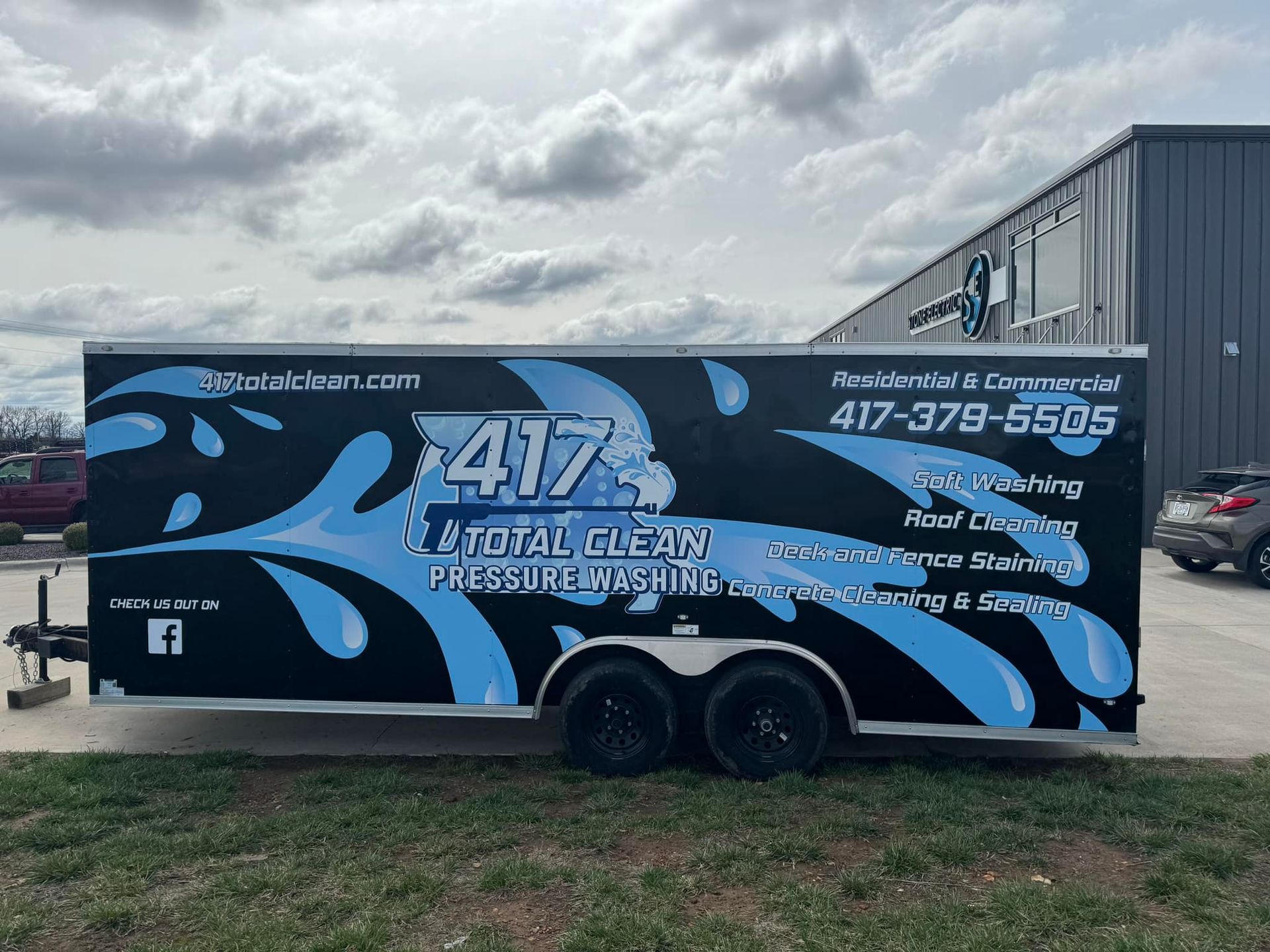 A black and blue trailer is parked in front of a building.