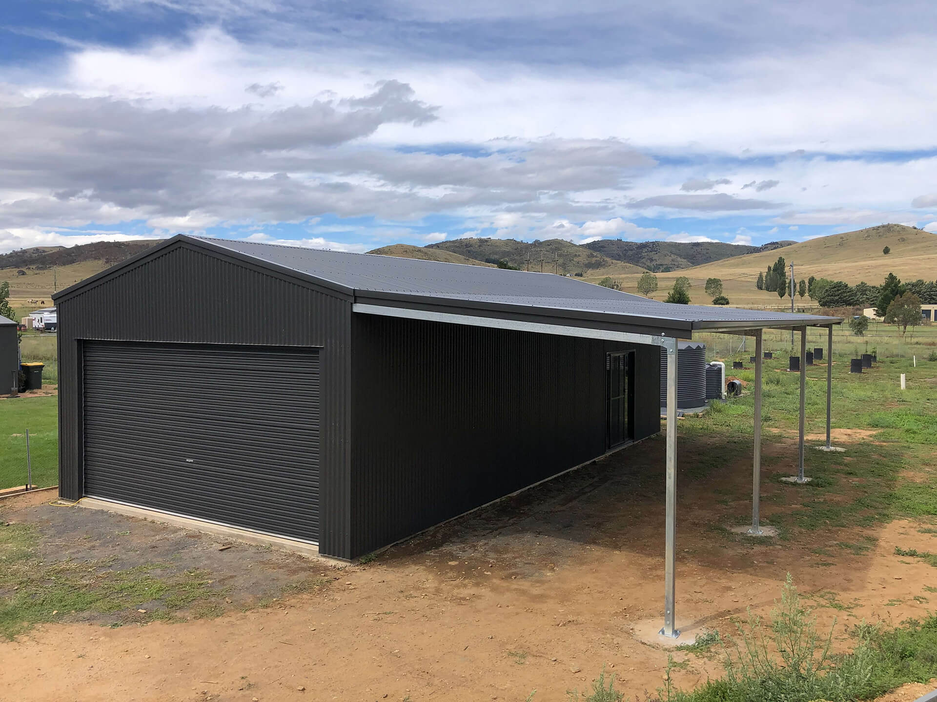 green shes with carport and grey door side view - Snowy Sheds